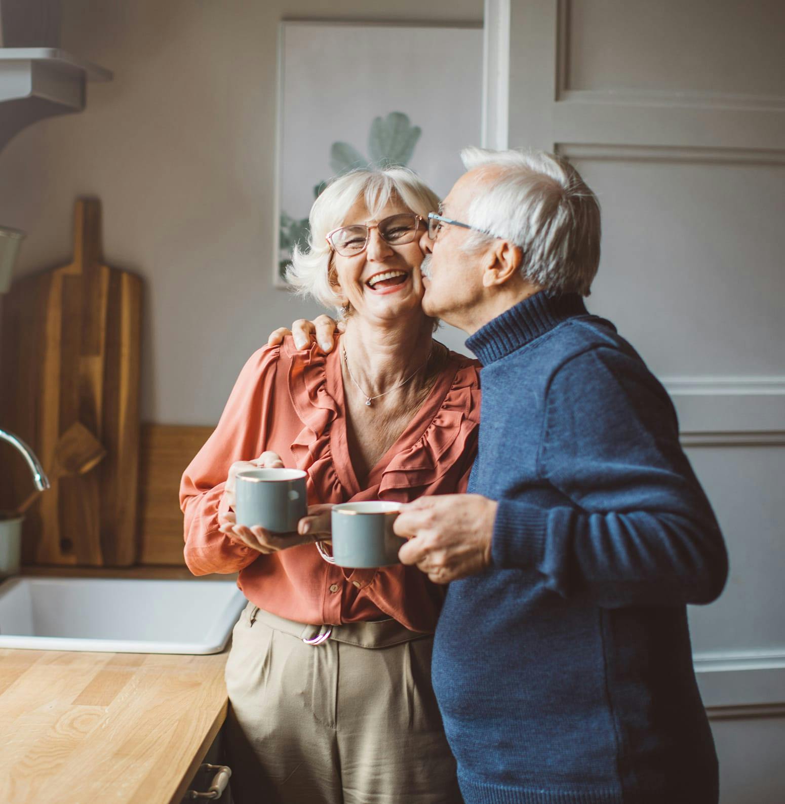 Man kissing womans cheek while they drink coffee