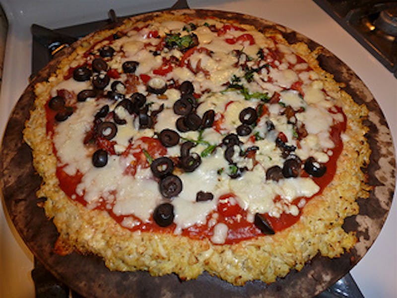 pizza on a wooden board on a stove top