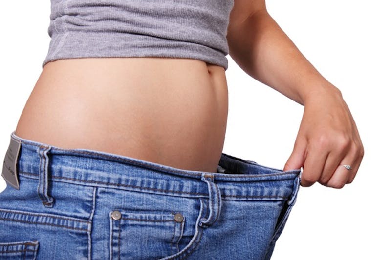 a close up of a woman's stomach with a pair of oversized jeans