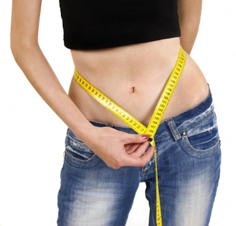 a close up of a woman measuring her waist with a tape