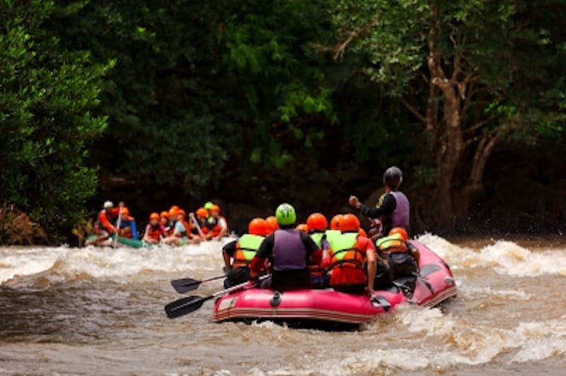 several people in a raft on a river with a group of people in life jackets