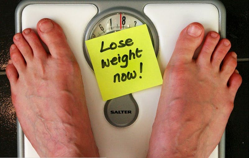 someone is standing on a scale with a sticky note on it that says lose weight now