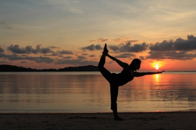 woman doing yoga on the beach at sunset