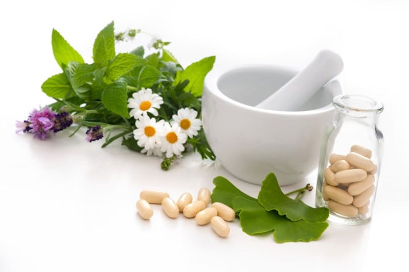 mortar and pesticide with flowers and herbs on white background