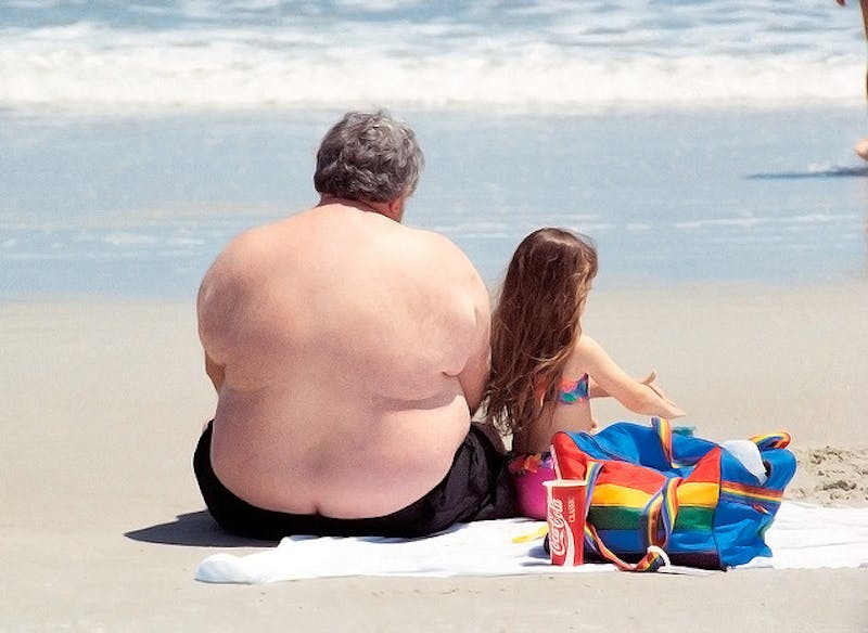 man and a little girl sitting on a towel on the beach