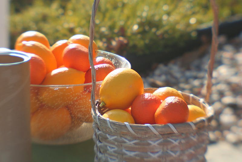 there are two baskets of oranges and lemons on a table outside