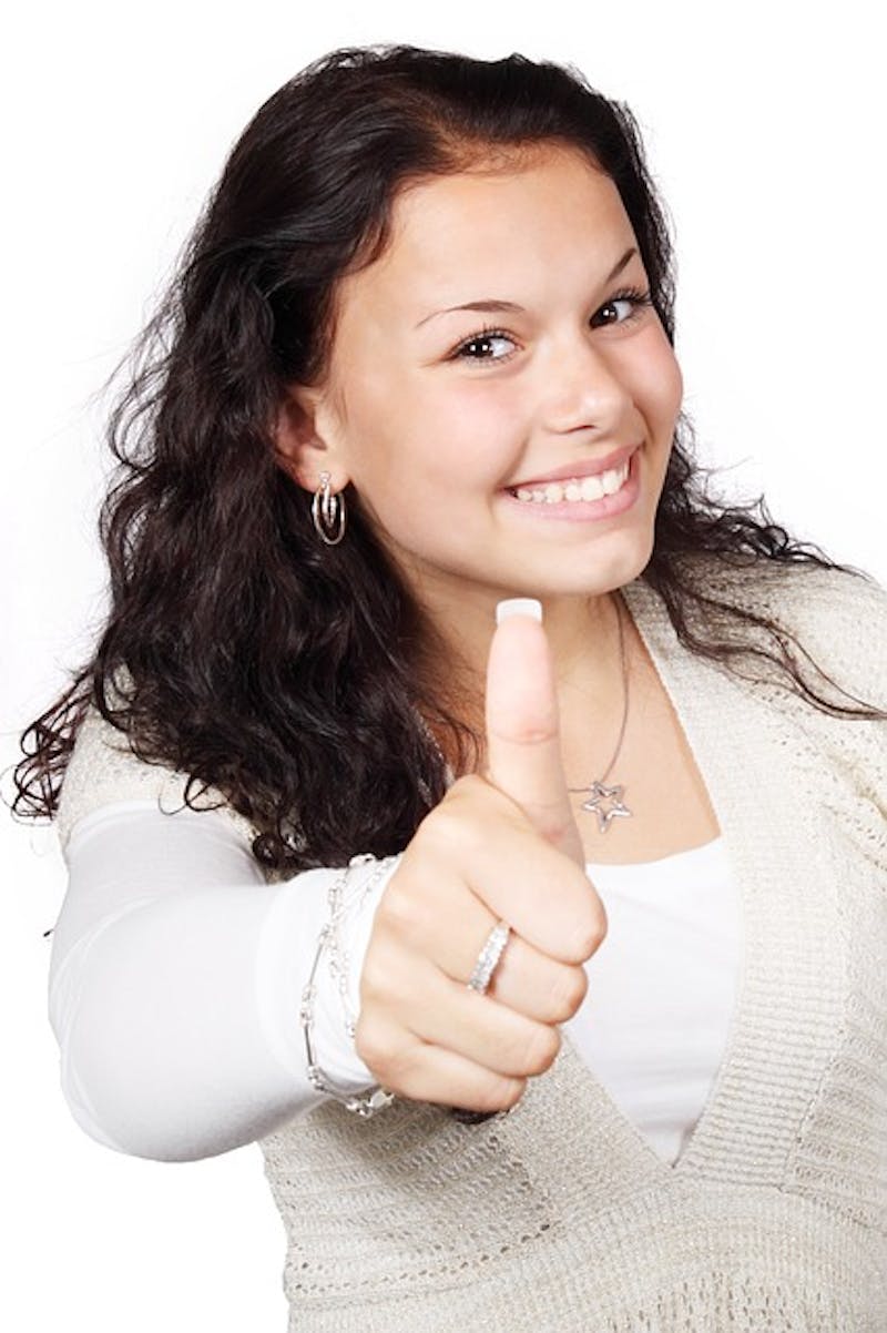 smiling woman with a thumbs up gesture in front of a white background