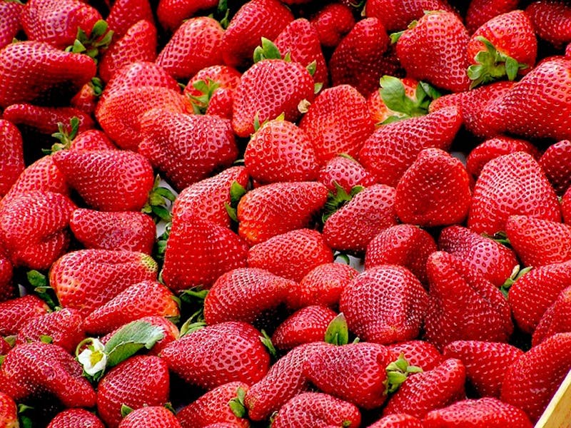 a close up of a box of strawberries with green leaves