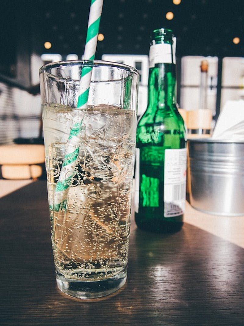 there is a glass of soda and a green bottle on a table