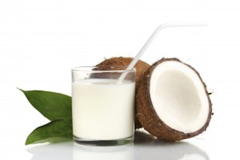 coconuts and a glass of coconut milk with a straw
