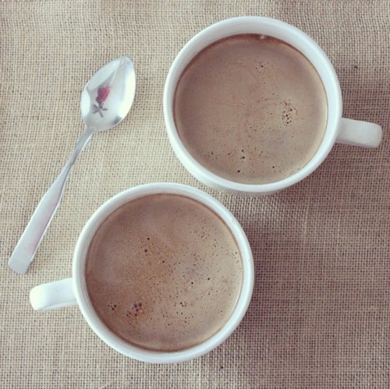 there are two cups of coffee on a table with a spoon