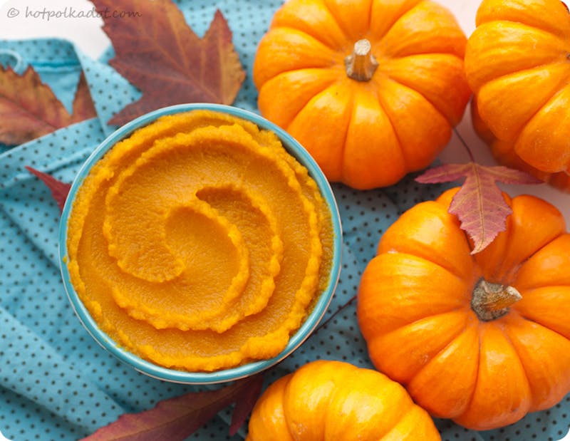 pumpkin butter in a bowl surrounded by small pumpkins and leaves