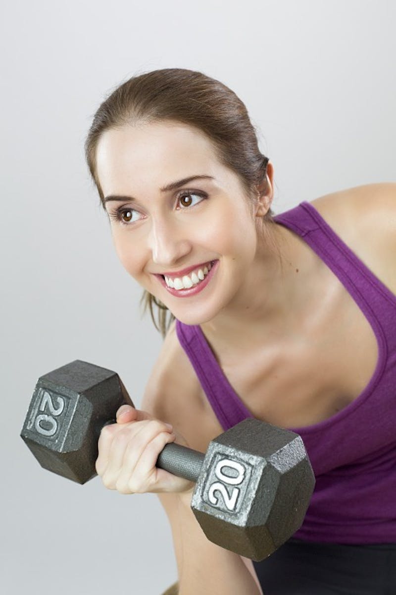 woman lifting a dumb bell with a smile on her face