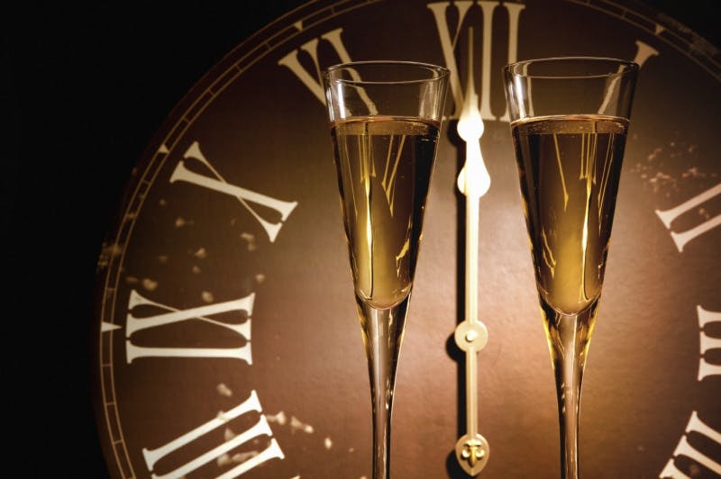 there are two glasses of champagne sitting next to a clock