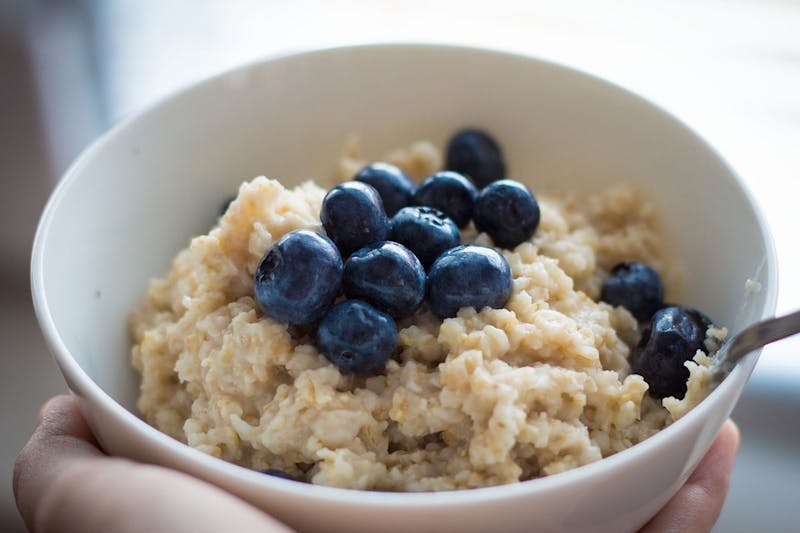 bowl of oatmeal with blueberries in it being held by a person