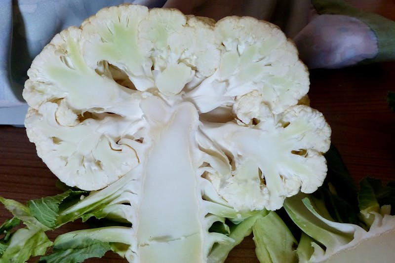 there is a head of cauliflower on a table with a knife