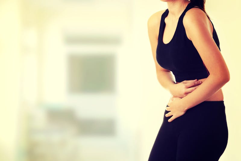 there is a woman with a stomach pain standing in a room