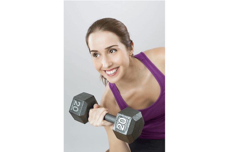 woman lifting a dumb bell with a smile on her face