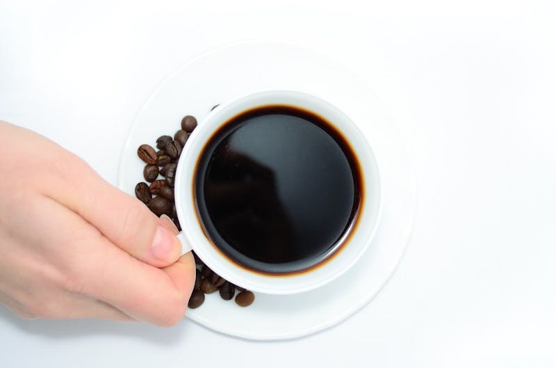 someone holding a cup of coffee with coffee beans on a saucer