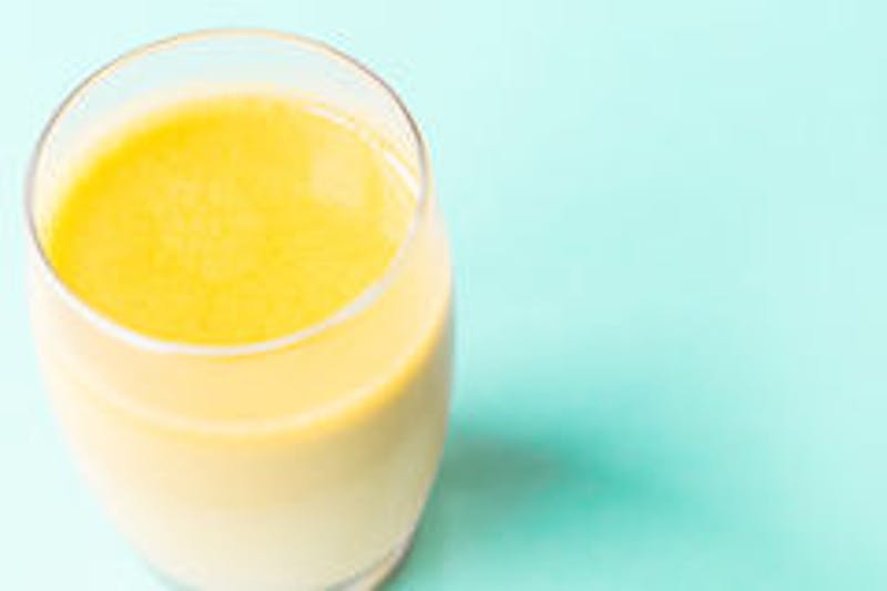 there is a glass of juice on a teal table
