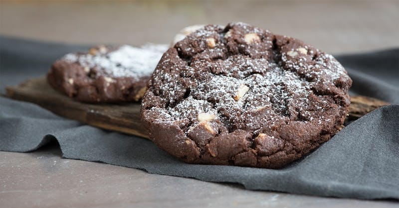 there are two cookies on a wooden board with powdered sugar