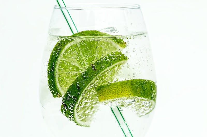 there is a glass of water with a slice of lime in it
