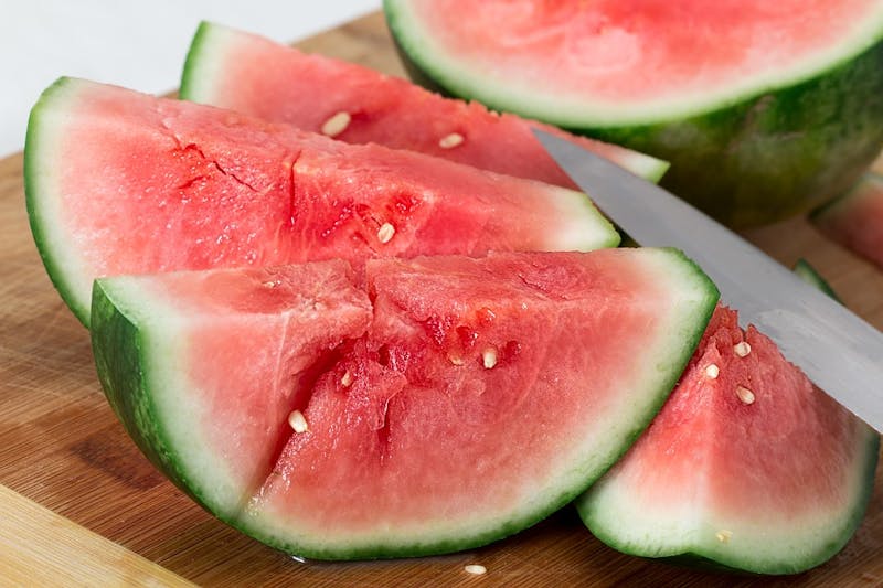 there is a knife that is cutting a piece of watermelon