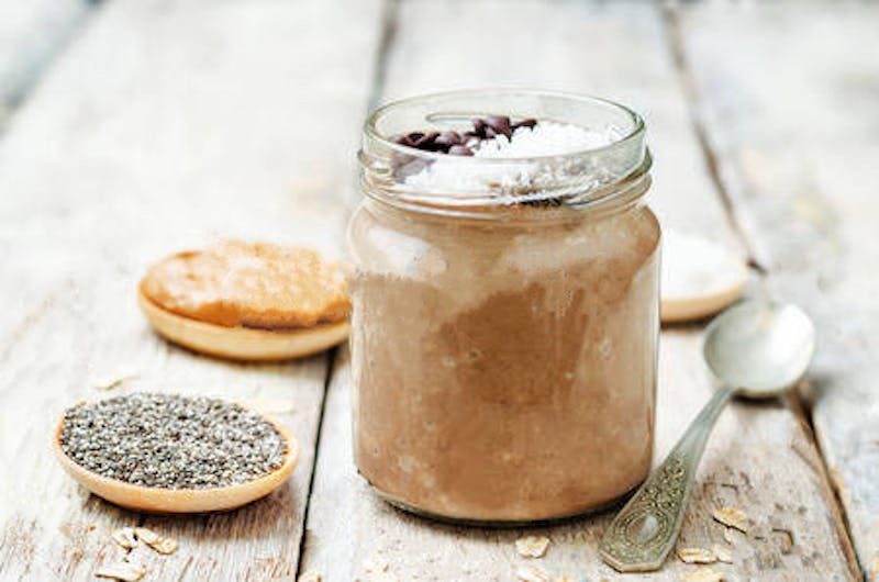 there is a jar with a dessert and a spoon on a table