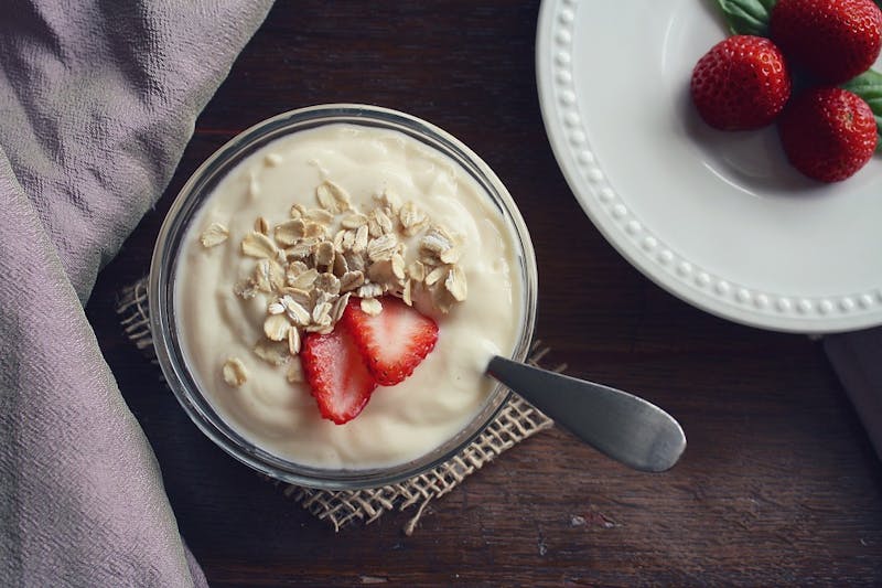 there is a bowl of yogurt with strawberries and a spoon