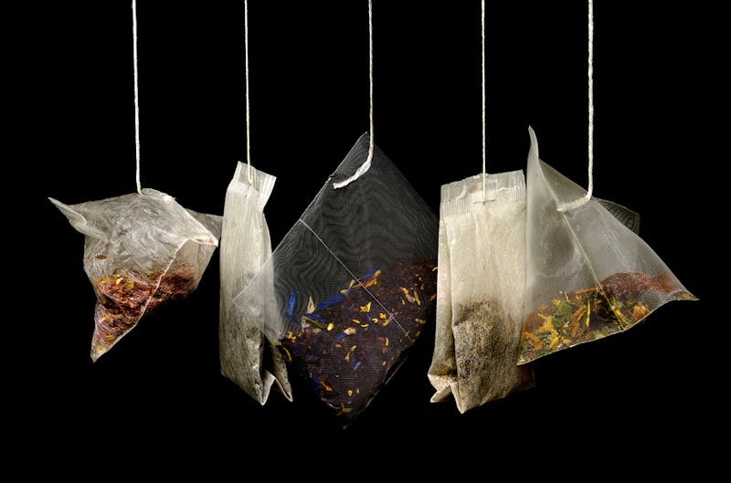 there are three bags of tea hanging from strings on a black background