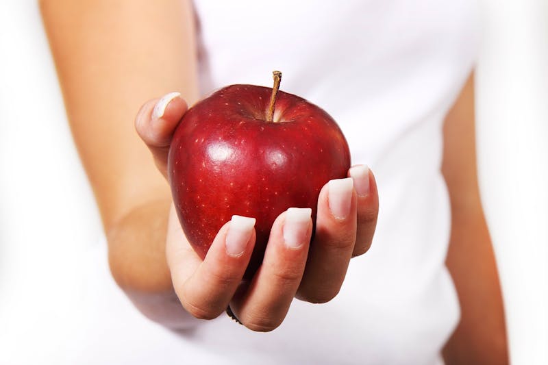 someone holding a red apple in their hands with a white shirt