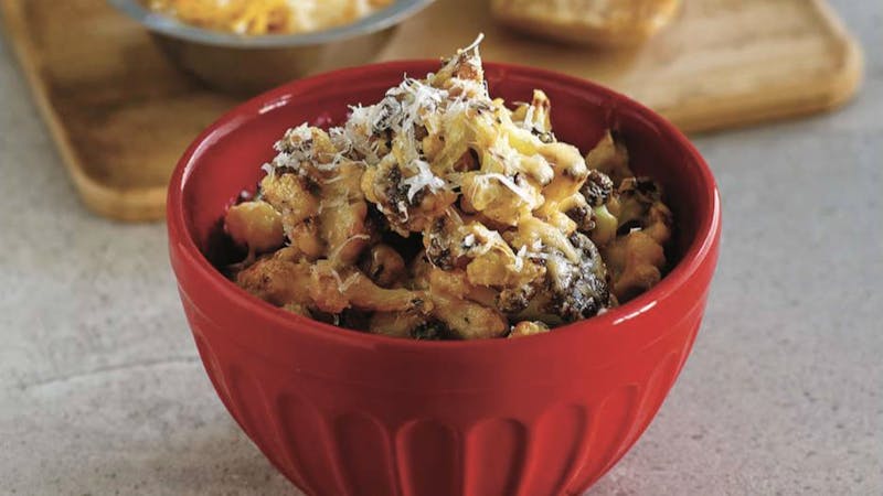 there is a red bowl of pasta with cheese and nuts