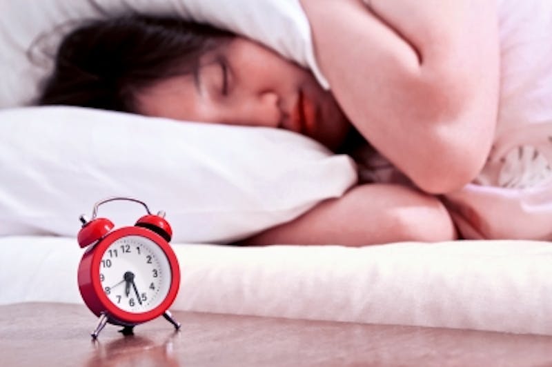 there is a woman sleeping in bed with an alarm clock