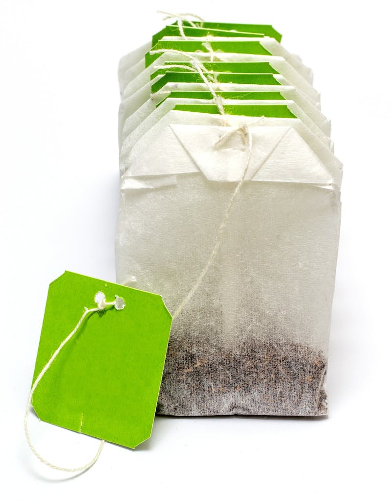 there are five bags of tea with a green tag on them