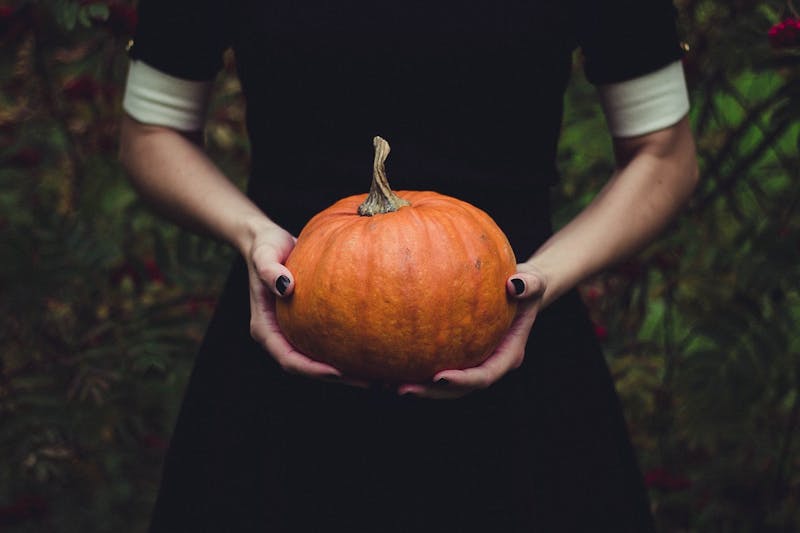 someone holding a pumpkin in their hands in a forest