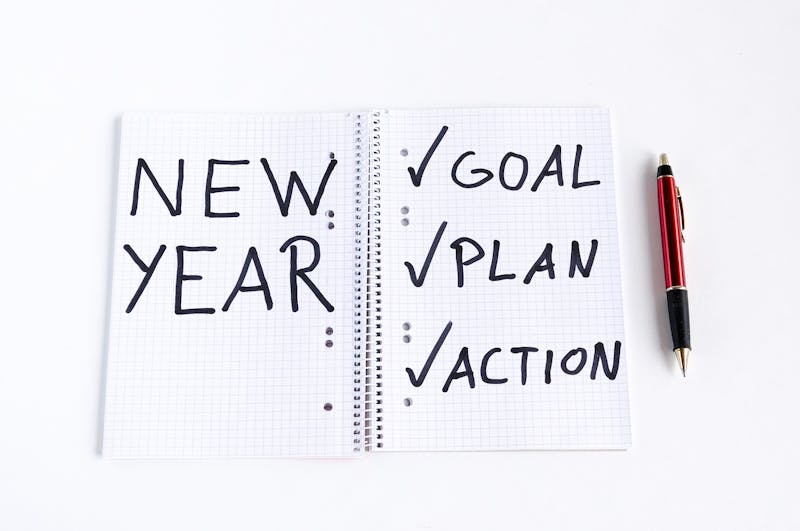 notebook with a pen and the words new year, plan, and action