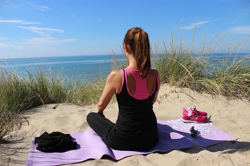 woman sitting on a beach with a towel and a pair of shoes