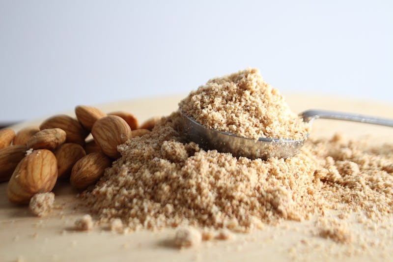 there is a spoon full of crushed almonds and a pile of nuts