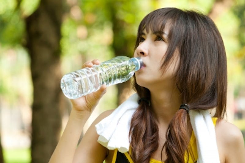 woman drinking water from a bottle in a park