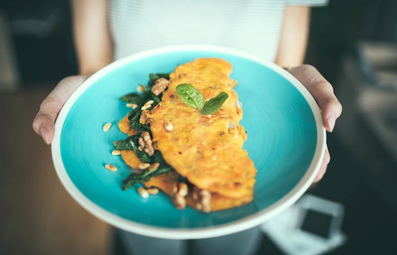 someone holding a plate of food with an omlette on it
