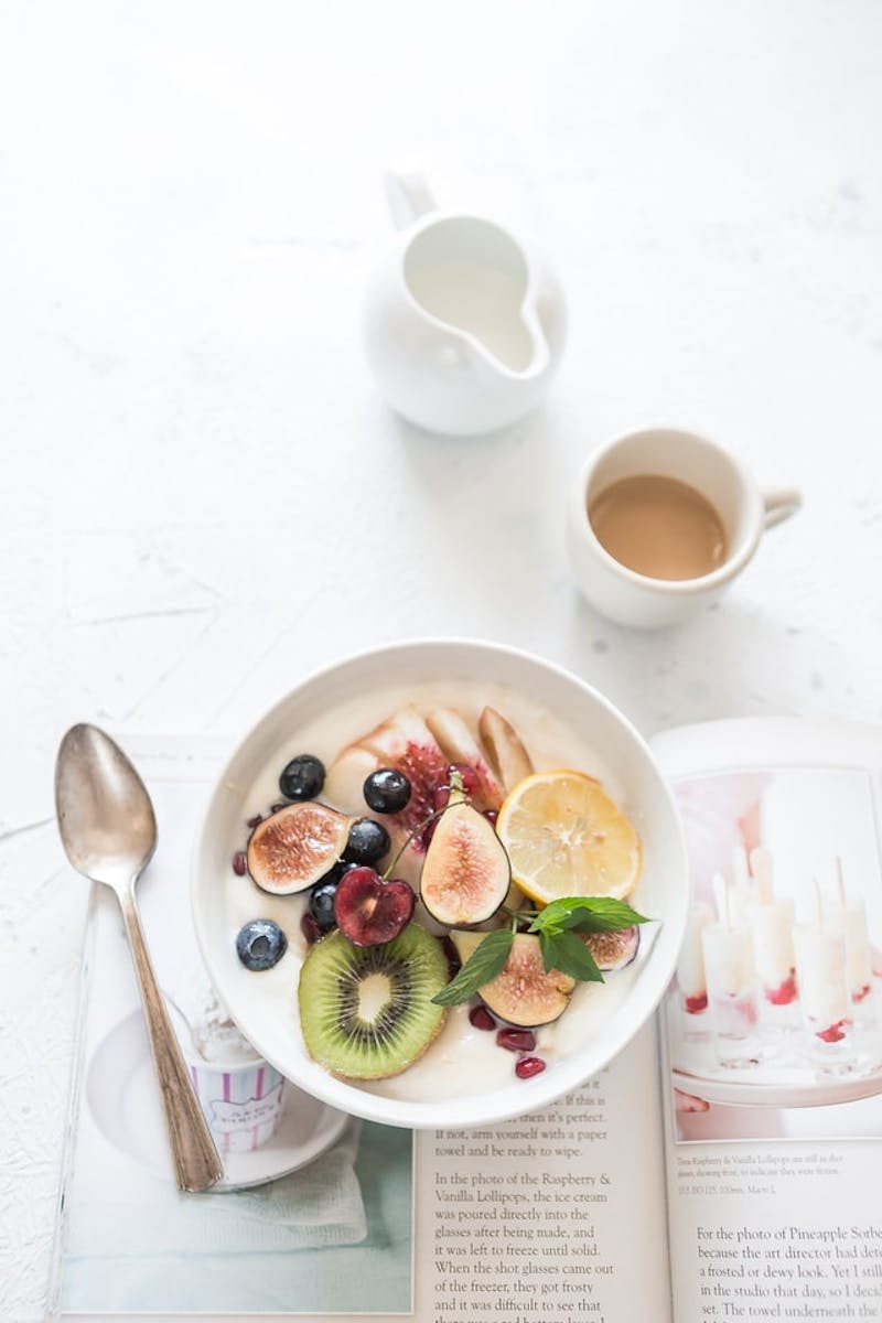 there is a bowl of fruit and a spoon on a table