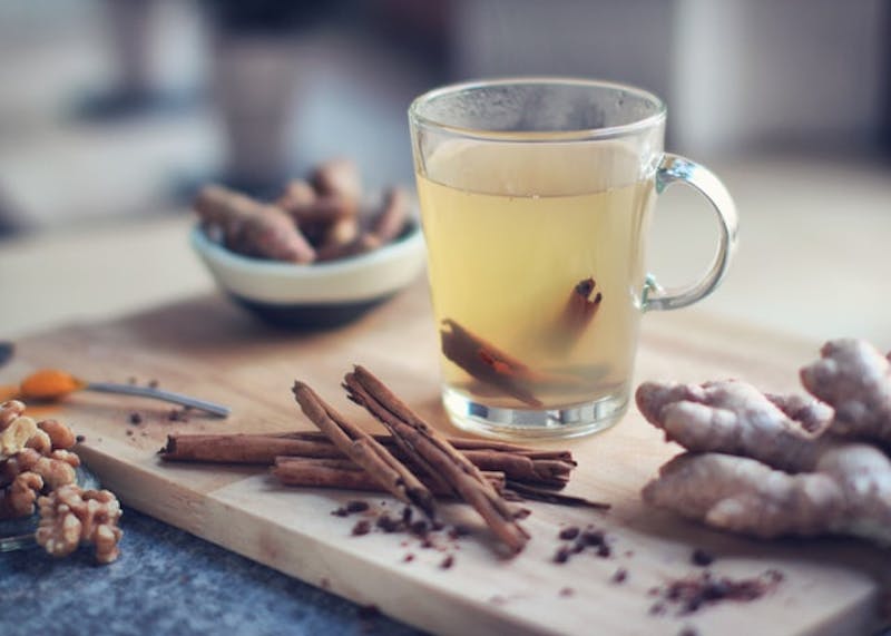 there is a cup of ginger tea and some spices on a cutting board