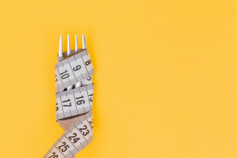 a close up of a fork with a measuring tape wrapped around it on a yellow background