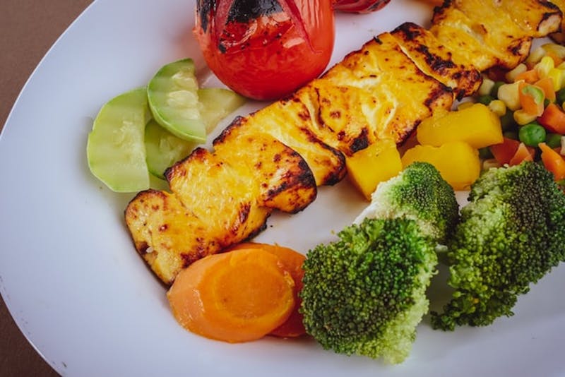 a plate of food with broccoli, tomatoes, and other vegetables