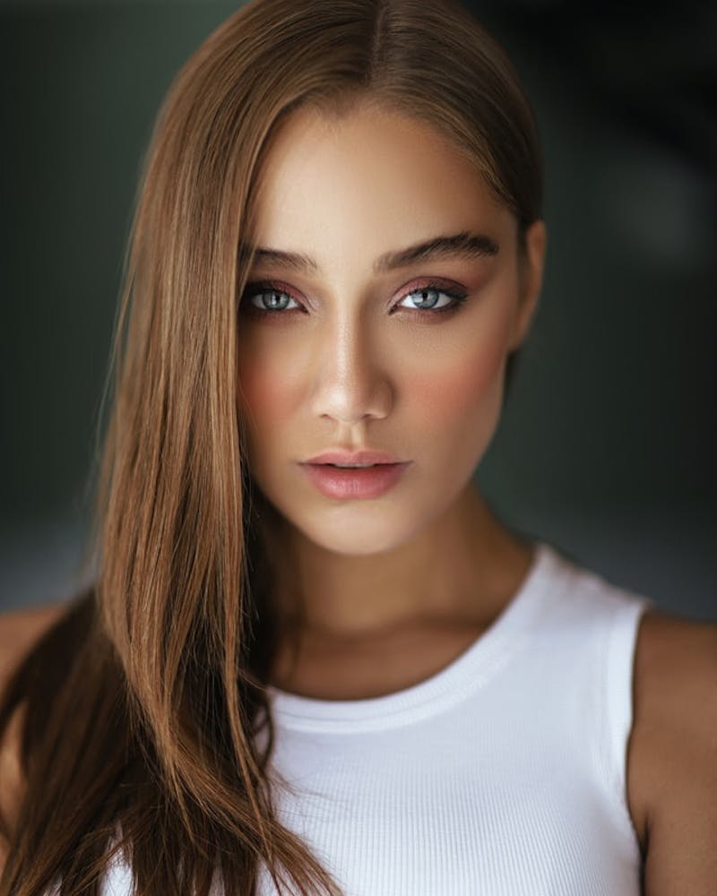 a close up of a woman with long hair and a white tank top