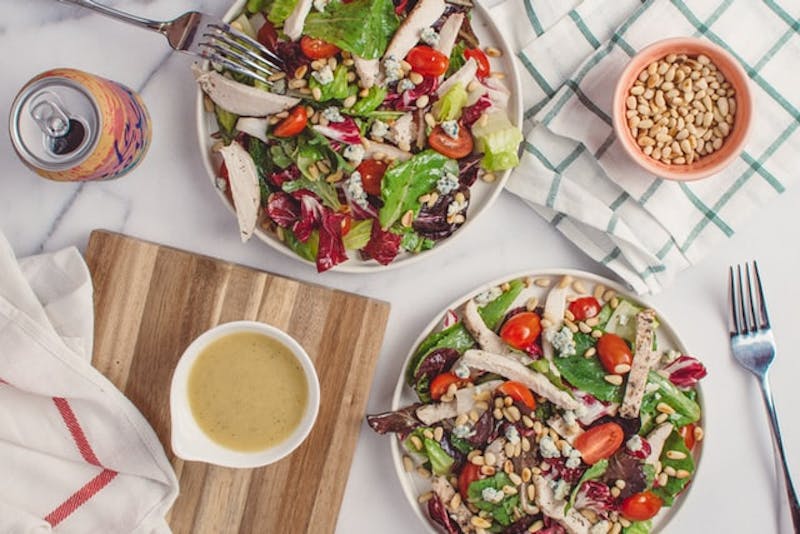 two plates of food on a table with a bowl of dressing