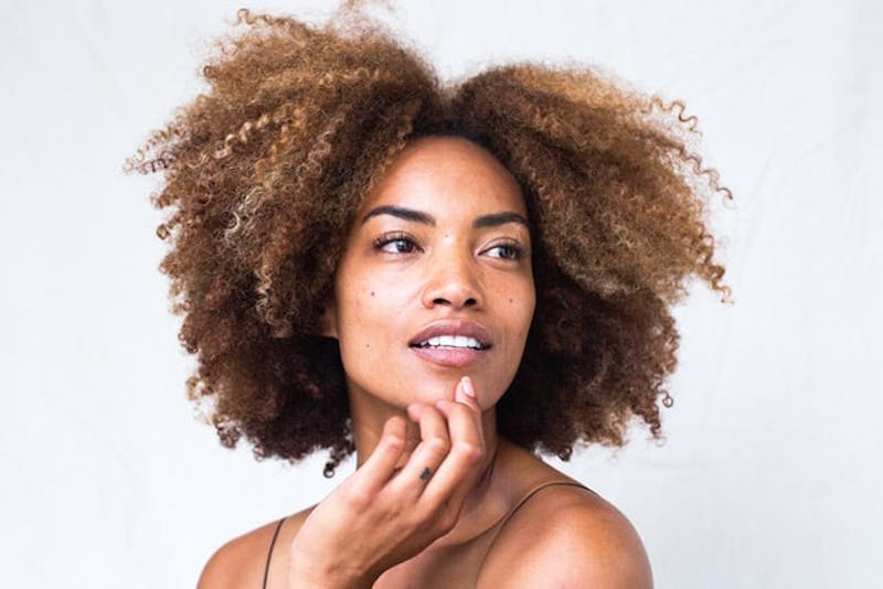 a close up of a woman with a curly hair looking to side while posing