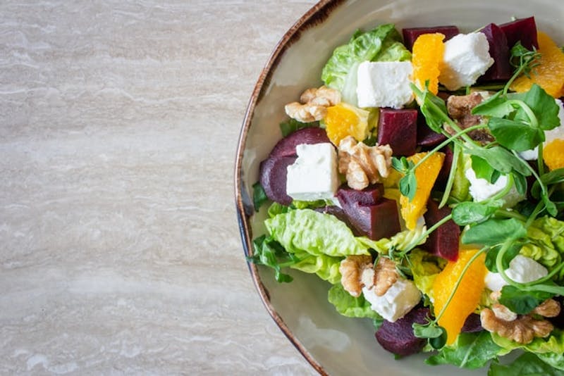 a bowl of salad with beets, oranges, and walnuts