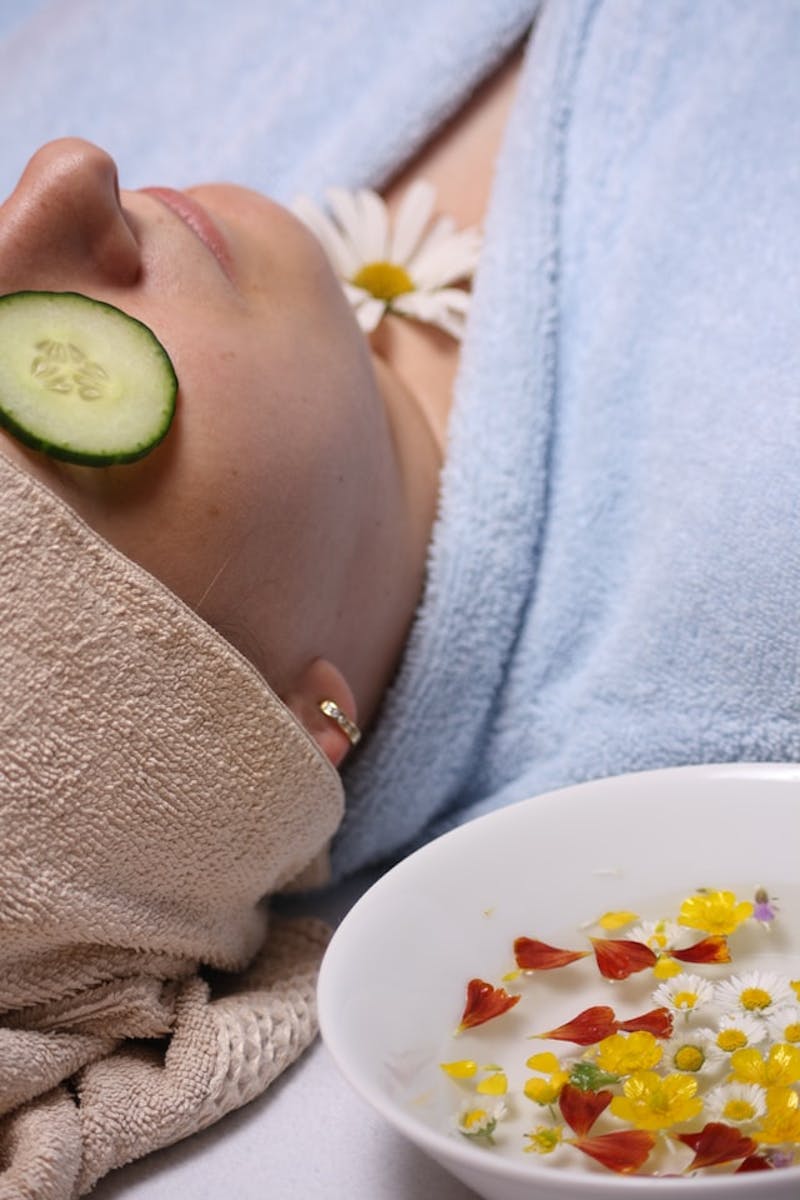 a woman laying down with cucumbers in eyes in a spa side shot