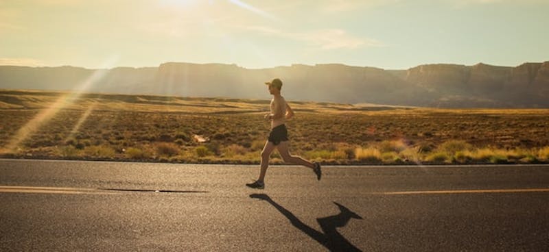 man running on a road in the desert